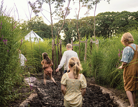 kinderen lopen het blotevoetenpad in de modder