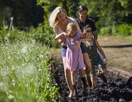 Een gezin loopt het blotevoetenpad in de modder